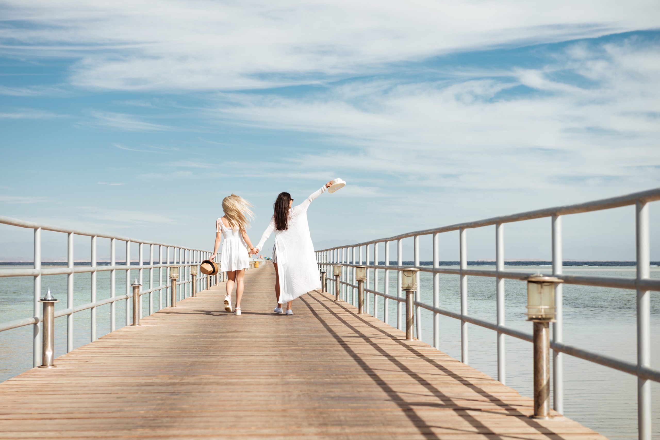 Back view of two young women walking on pier together Map and travel planning scene — stock photo for trip planning